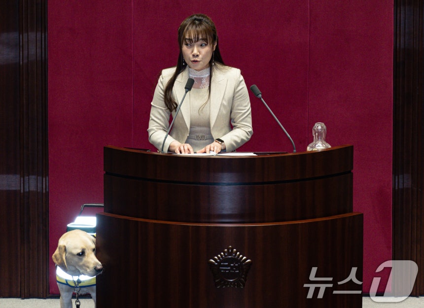 김예지 국민의힘 의원의 안내견 '태백'이가 13일 오후 서울 여의도 국회 본회의장에서 열린 제423회 국회(임시회) 제1차 본회의에서 김 의원이 보건복지위원회 소관 제안설명 및 심사보고를 하는 동안 발언대 주위를 살