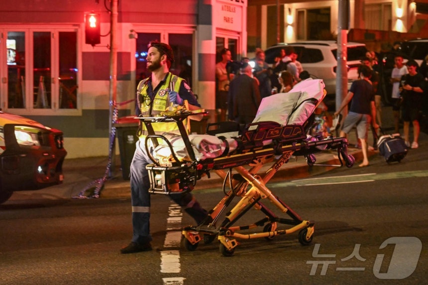 14일(현지시간) 호주 시드니 본다이 비치에서 총격 사건이 발생한 가운데,의료진들이 피해자들을 병원으로 후송하고 있다.ⓒ AFP=뉴스1