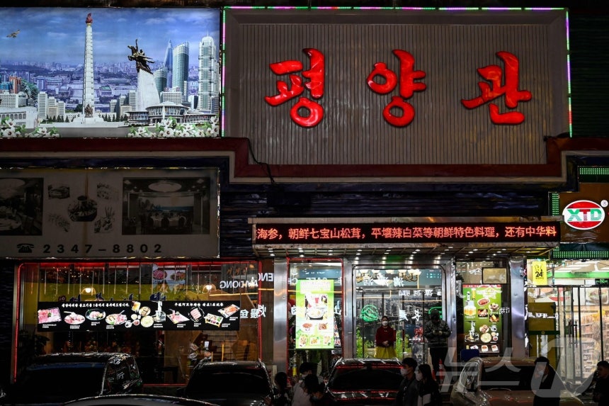 2023년 3월 31일 중국 북동부 랴오닝성 선양의 한 북한 마을에 있는 북한 식당 입구에 마스크를 쓴 북한 노동자가 서 있다.2023.03.31.ⓒ AFP=뉴스1 ⓒ News1 이정환 기자