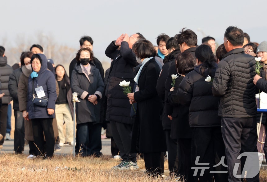 179명이 사망한 12·29 제주항공 무안공항 참사 1주기인 29일 전남 무안공항에서 유가족들이 활주로 내 피해를 키운 원인으로 지목된 방위각 시설물(로컬라이저)을 가까이서 바라보고 있다.한 유가족이 희생자 이름을