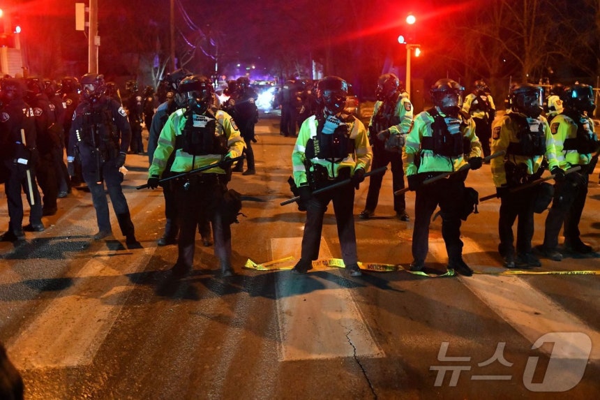 14일(현지시간) 미네소타주 미니애폴리스에서 시위대가 연방 법집행관과 충돌한 뒤 주 경찰관들이 도로에 줄을 지어 섰다.이날 시 당국은 이민세관단속국(ICE) 요원이 베네수엘라 출신 남성을 총격했다고 밝혔다.당국은
