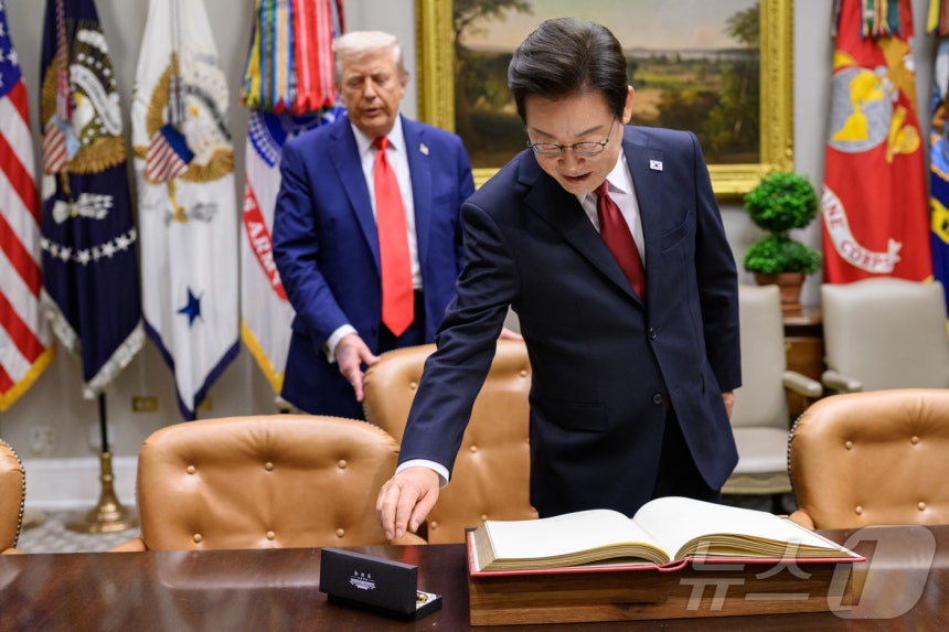 지난 8월 25일(현지시간) 이재명 대통령이 한미정상회담에 앞서 미 백악관 루즈벨트룸에서 방명록에 서명하려고 펜을 잡으려는 순간 도널드 트럼프 미국 대통령이 뒤에서 의자를 당겨 주고 있다.(백악관 제공.재판매 및