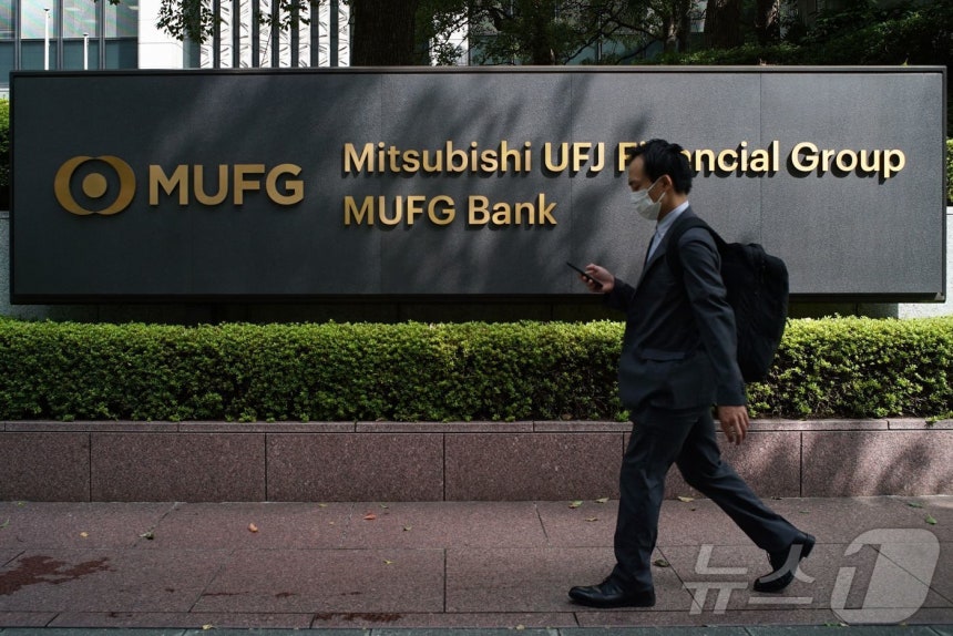 일본 도쿄에 있는 미쓰비시 UFJ 파이낸셜 그룹과 MUFG 은행 본사 앞 간판을 한 보행자가 지나가고 있다. 2021.9.22. ⓒ AFP=뉴스1