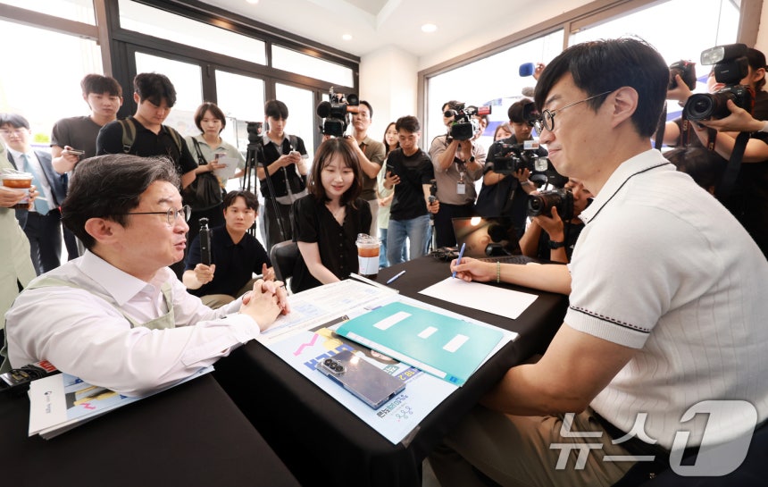 이억원 금융위원장이 1차 '청년미래적금' 가입 신청이 시작된 지난 6월 서울 성동구 신한빌딩에서 상담받는 청년들과 대화를 나누고 있다. 2026.6.22 ⓒ 뉴스1 이호윤 기자
