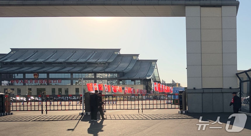 신압록강대교 정식 개통을 하루 앞둔 14일 중국 랴오닝성 단둥의 중국 측 해관(세관) 입구에서 공안들이 경비를 서고 있다. 시설 안에는 오성홍기와 인공기가 나란히 내걸려 있고, 인근에는 여러 차량이 주차돼 있다. 2