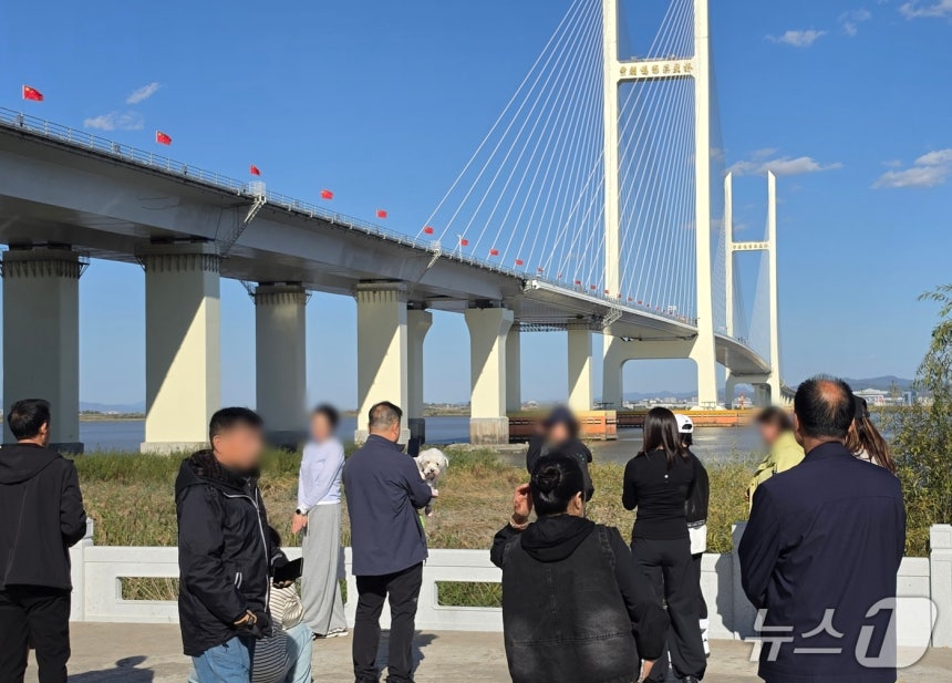 신압록강대교 정식 개통을 하루 앞둔 14일 중국 랴오닝성 단둥의 대교 인근에 관광객들이 모여 있다. 뒤로 보이는 대교 중국 측 구간에는 오성홍기가 줄지어 내걸려 있다. 2026.10.14. ⓒ 단둥=뉴스1 노민호 특