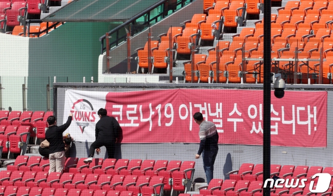 14일 오후 서울 송파구 잠실야구장에서 프로야구 LG트윈스 관계자들이 응원단석 앞에 '코로나19 이겨낼 수 있습니다' 문구가 적힌 현수막을 걸고 있다. 한편, 이날 한국야구위원회(KBO)는 긴급이사회를 열고 10개 프로야구단 사장들과 신종 코로나바이러스 감염증(코로나19)로 연기된 시즌 개막 및 주요 사안을 논의했다. 2020.4.14 ⓒ 뉴스1 이동해 기자