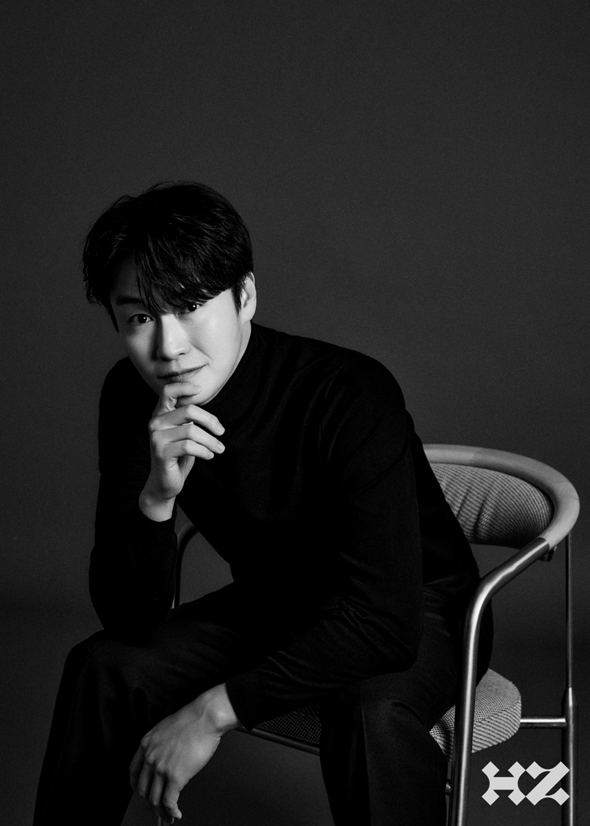 黒い服で椅子に座る俳優オ・ウィシクのモノクロポートレート