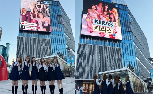 新村の大型ビジョンを背に、制服風衣装で並ぶKIIRASのメンバー