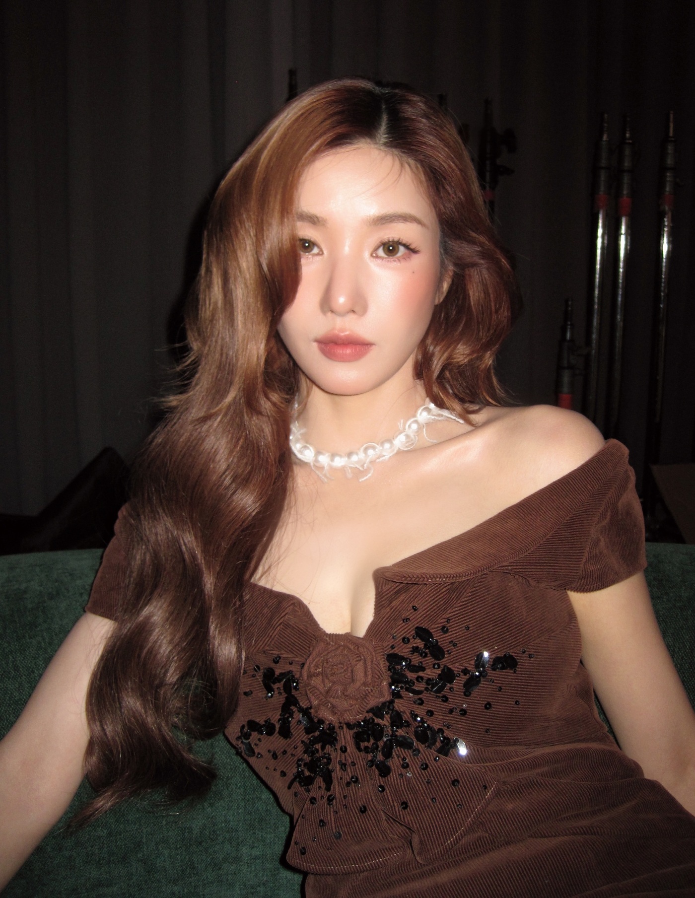 ブラウンのオフショルダードレスとウェーブヘア姿でカメラを見つめるクォン・ウンビ