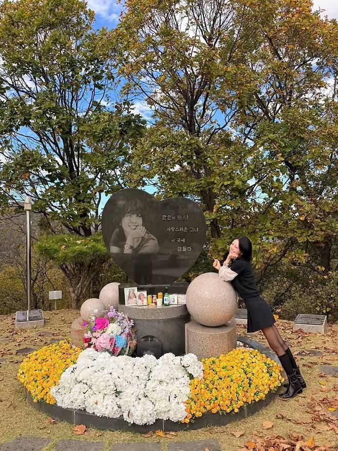 母チェ・ジンシルさんの墓前で、墓碑の写真と同じように頬に手を添えてほほ笑むチェ・ジュニ