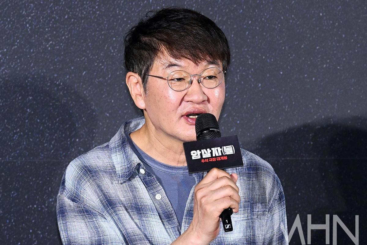 映画『暗殺者たち』のロゴが入ったマイクを手に、話すホ・ジノ監督