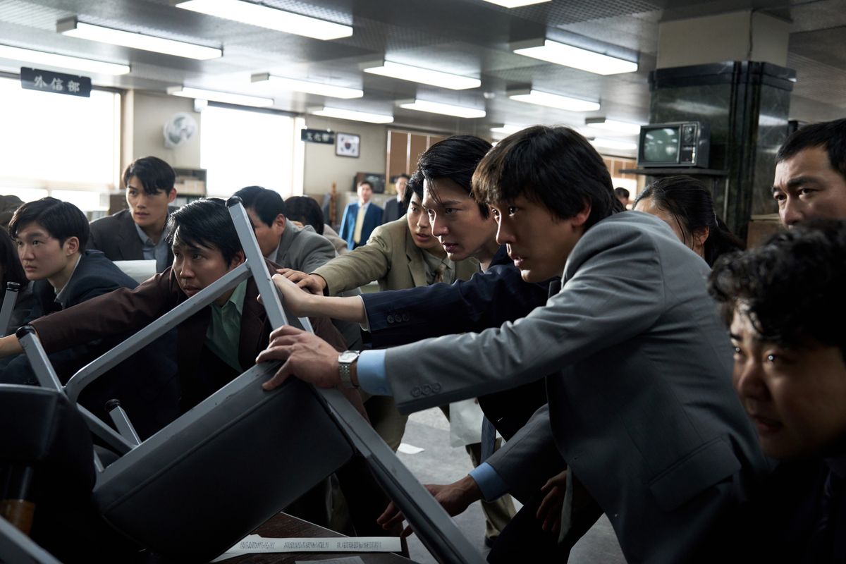 映画『暗殺者たち』のスチール。ユ・ヘジン、パク・ヘイルらが机に身を乗り出し、捜査にあたる