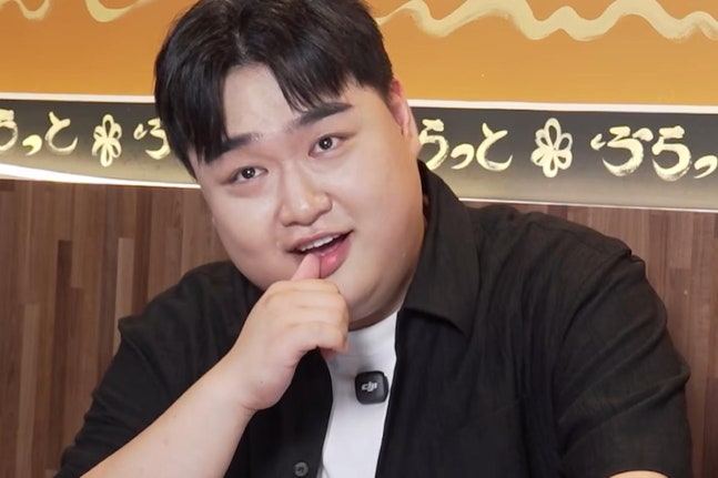 黒いシャツ姿でカメラに向かって話すコメディアンのキム・ギュウォン