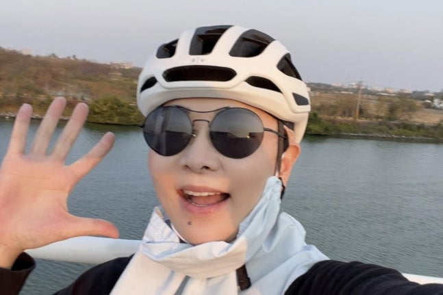 自転車用ヘルメットとサングラスを着け、手を振るチャン・スギョン