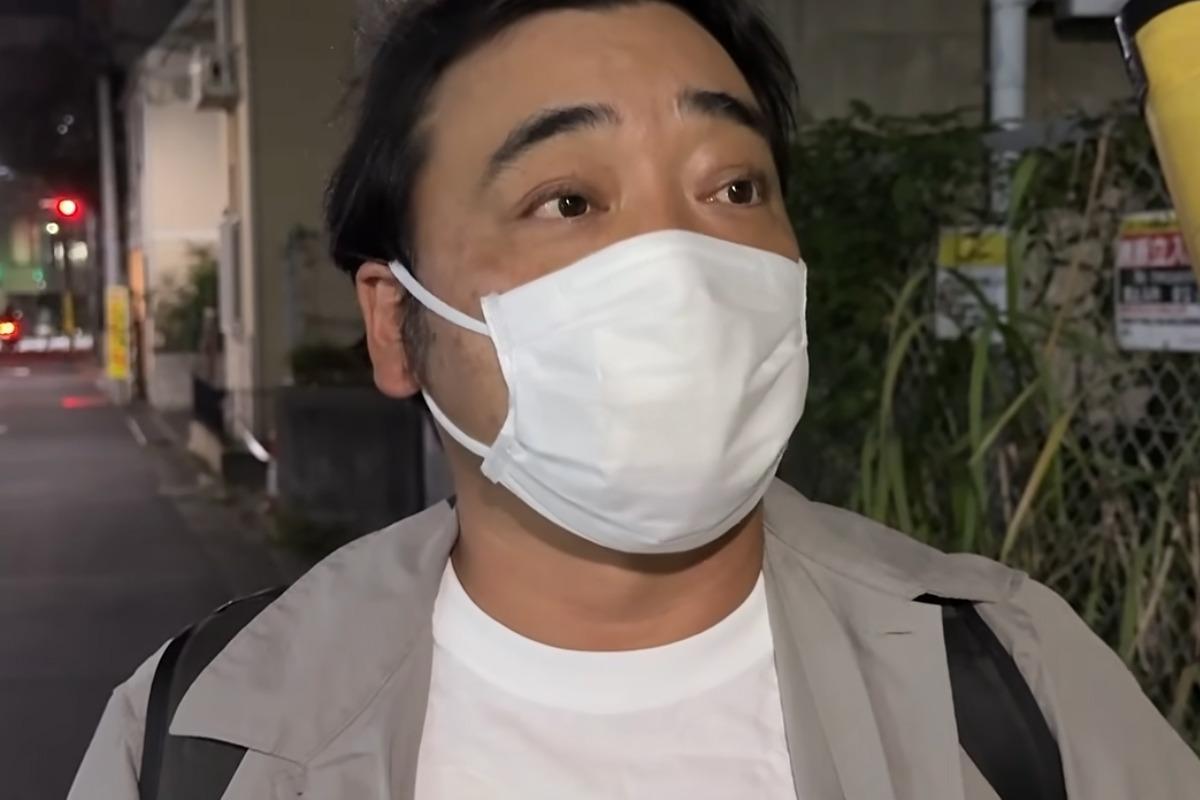 夜の街でマスクを着けて話す斉藤慎二