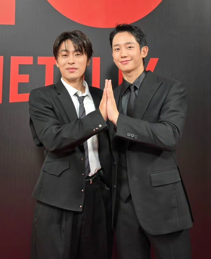 Netflixのイベント会場で、黒いスーツ姿で並び手を合わせるチョン・ヘインとク・ギョファン