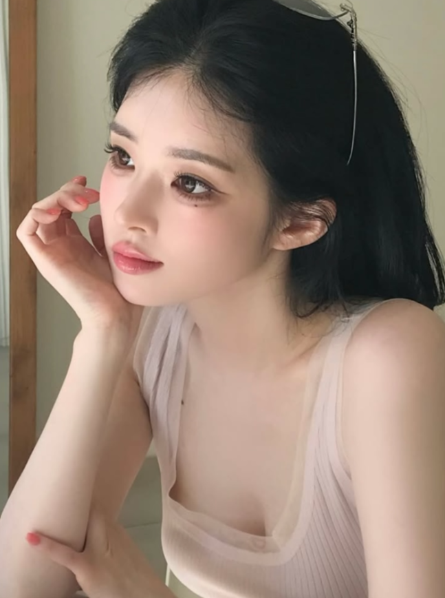 窓辺で頬に手を添える、淡いピンクのトップス姿のユ・ヘウォン