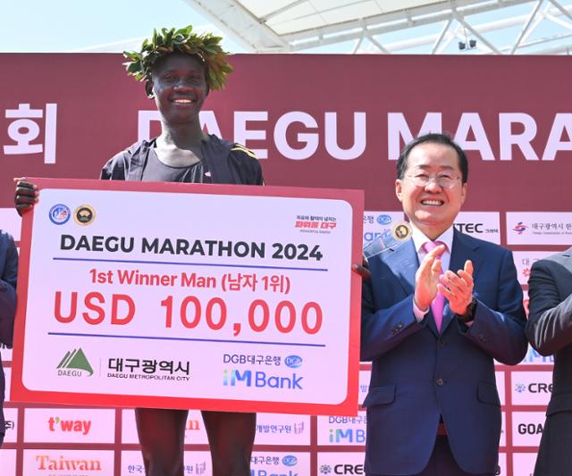 홍준표(오른쪽) 대구시장이 지난 7일 대구마라톤대회에서 2시간 7분 3초로 우승한 케냐의 스테픈 키프롭에게 우승 월계관과 상금을 시상하고 격려하고 있다. 우승 상금은 16만 달러까지 가능하지만 기록별로 상금을 주는 