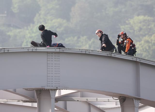 신원 불명의 남성이 17일 오전 서울 용산구 한강대교 아치 위에 올라가 소방대원들과 경찰이 출동해 있다. 연합뉴스