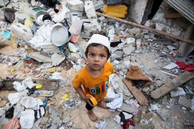 한 팔레스타인 어린이가 1일 가자지구 남부 라파의 무너진 주택 잔해 위에 서 있다. 라파=로이터 연합뉴스