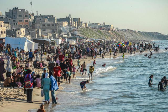 팔레스타인 피란민들이 지난달 17일 가자지구 중부 데이르 알발라의 해변에서 시간을 보내고 있다. 데이르 알발라=AFP 연합뉴스