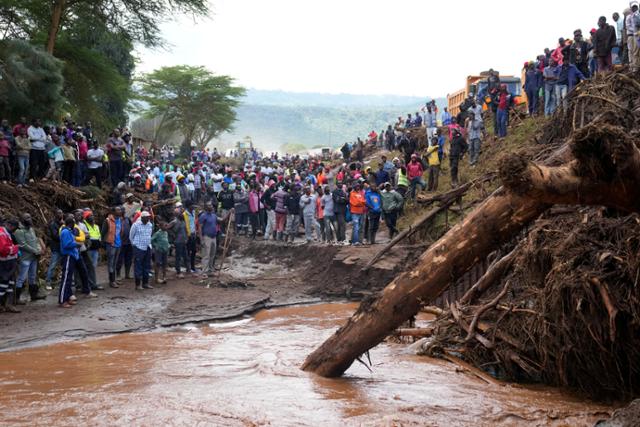 아프리카 케냐 나쿠루카운티의 카무치리 마을 주민들이 지난달 30일 홍수로 가옥이 떠내려간 뒤, 한 여성의 시신이 발견된 다리 인근에 모여 있다. AP 연합뉴스