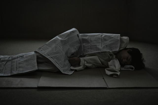 드라마 '더 에이트 쇼'에서 게임에 참가한 배진수(류준열)가 방에서 신문지를 덮고 자고 있다. 넷플릭스 제공