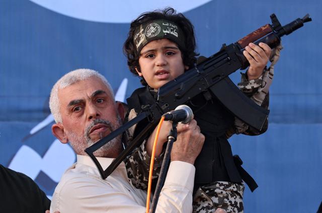 하마스 지도자 야히아 신와르(왼쪽)가 2021년 가자지구 북부 가자시티에서 열린 연설회에서 이스라엘과의 교전 중 사망한 하마스 군사 조직인 알카삼 여단 대원의 아이를 들어 올리고 있다. 가자=AFP 연합뉴스