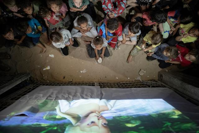 팔레스타인 가자지구 어린이들이 지난달 28일 최남단 도시 라파 난민촌에서 국제 구호단체가 임시 상영한 만화영화를 보고 있다. 라파=EPA 연합뉴스