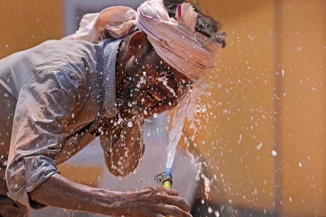 지난달 27일 인도 우타르프라데시주 러크나우에서 한 남성이 호스로 얼굴에 물을 뿌리며 더위를 식히고 있다. 인도 일부 지역에서는 낮 최고 기온이 50도에 육박하는 등 기록적인 고온 현상이 나타나고 있다. 러크나우=A