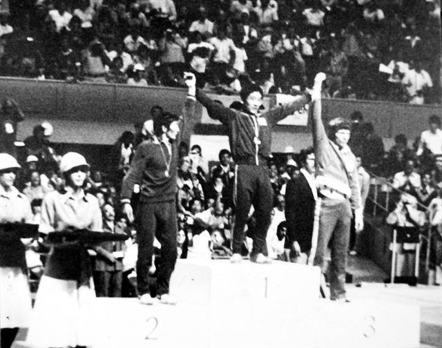 1976년 몬트리올 올림픽 레슬링에서 금메달을 딴 양정모(가운데)가 시상대 맨 위에 서 있다. 한국일보는 양정모가 대한민국 사상 첫 금메달을 획득하자 헤드라인에 ‘양정모, 숙원의 첫 금메달’ 제목의 기사로 대서특필했