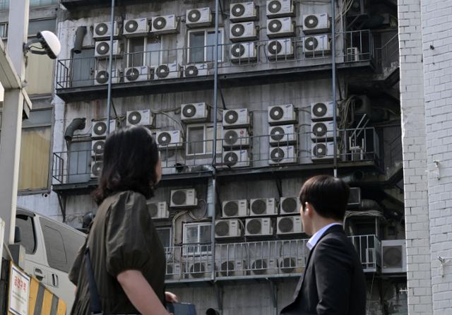 지난해 5월 15일 서울 시내 건물 외벽에 설치된 에어컨 실외기 앞으로 사람들이 지나가고 있습니다. 한국은 전 세계에서도 에어컨 보급률이 손꼽히게 높은 편입니다. 국제에너지기구(IEA) 2018년 보고서에 따르면 일