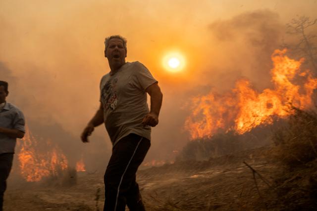 그리스에 섭씨 40도 이상의 폭염이 이어지던 지난해 7월 25일 남동부 로도스섬에 산불이 한 마을로 번지자 주민들이 서둘러 대피하고 있다. AP 연합뉴스