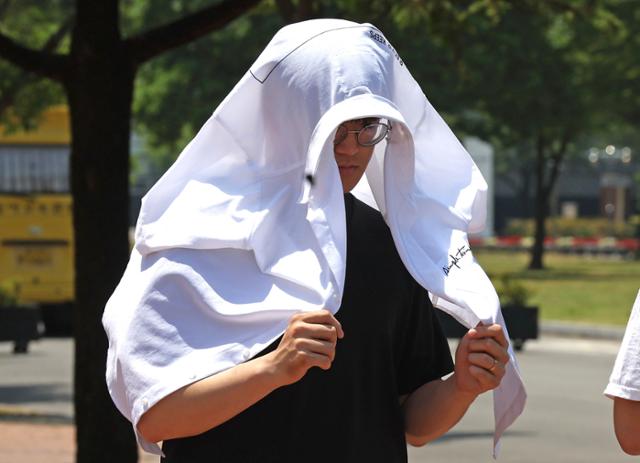 10일 경북 경산시 영남대 정문에서 한 학생이 햇빛을 피하기 위해 셔츠를 머리에 둘러쓴 채 걷고 있다. 이날 경산에는 폭염주의보가 발령됐다. 폭염주의보는 일 최고체감온도가 33도 이상인 상황이 이틀 이상 지속할 것으
