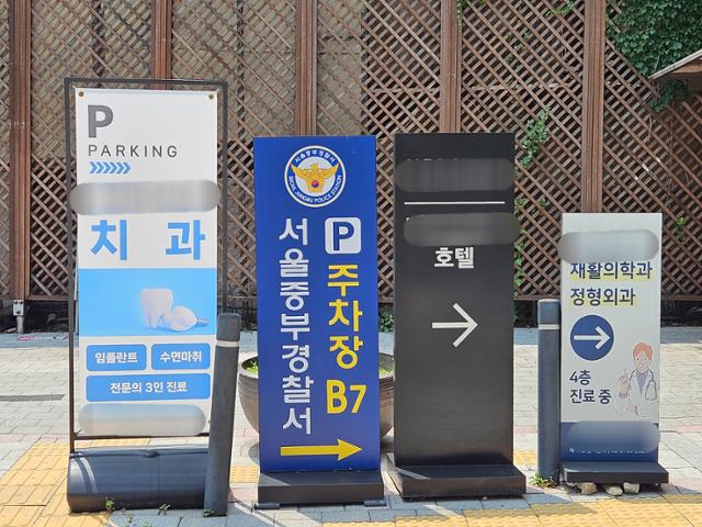 서울 회현역 인근에 위치한 상가 건물에 임시 청사를 꾸린 서울중부경찰서의 주차장을 안내하는 표지판이 같은 건물에 입주한 병원 등의 팻말과 함께 놓여 있다. 이유진 기자