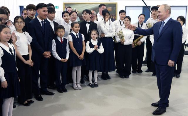 블라디미르 푸틴(맨 오른쪽) 러시아 대통령이 18일 러시아 극동 야쿠츠크에 있는 사하(야쿠티야) 공화국 고등 음악학교을 방문해 학생들을 격려하고 있다. 야쿠츠크=로이터 연합뉴스