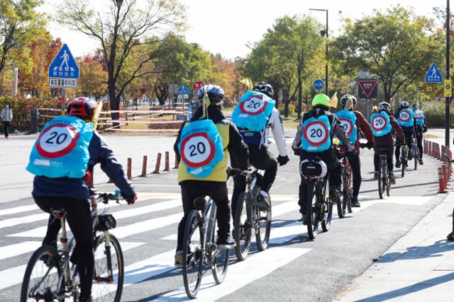 시민 자원봉사자들이 한강공원 자전거도로에서 20km 표시가 그려진 가방 덮개를 착용하고 안전 홍보 캠페인을 하고 있습니다. 서울시 제공