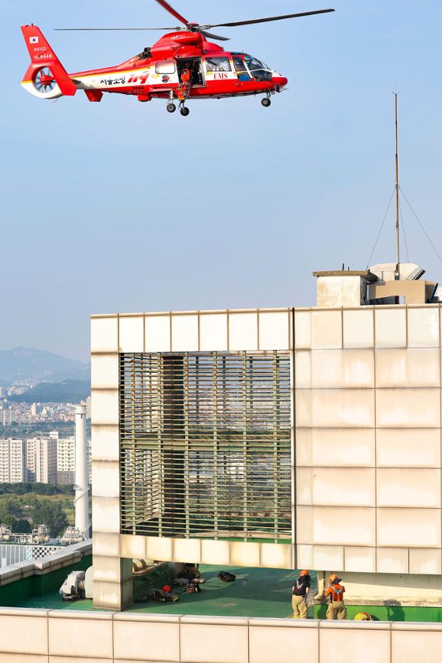 19일 서울 양천구 목동에 있는 23층짜리 아파트 화재 현장에서 소방관들이 헬기를 이용해 옥상에 대피한 사람을 구조하고 있다. 연합뉴스