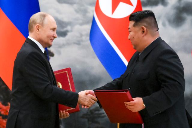 블라디미르 푸틴(왼쪽) 러시아 대통령과 김정은 북한 국무위원장이 19일 북한 평양 금수산 영빈관에서 '포괄적 전략 동반자 협정'을 체결한 후 협정서를 들고 악수하고 있다. 평양=AP 뉴시스