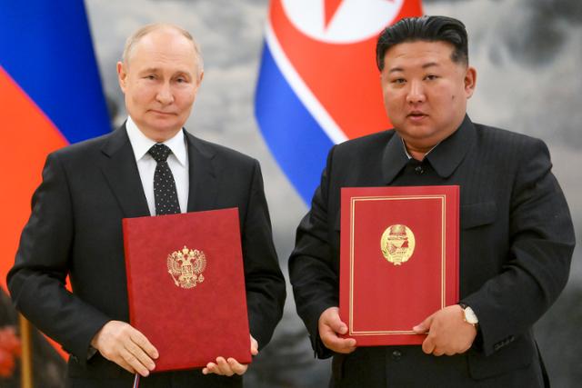 블라디미르 푸틴(왼쪽) 러시아 대통령과 김정은 북한 국무위원장이 19일 북한 평양 금수산 영빈관에서 '포괄적 전략 동반자 협정'을 체결한 후 협정서를 들고 기념 촬영하고 있다. 이번 협정에는 어느 한 나라가 공격을 