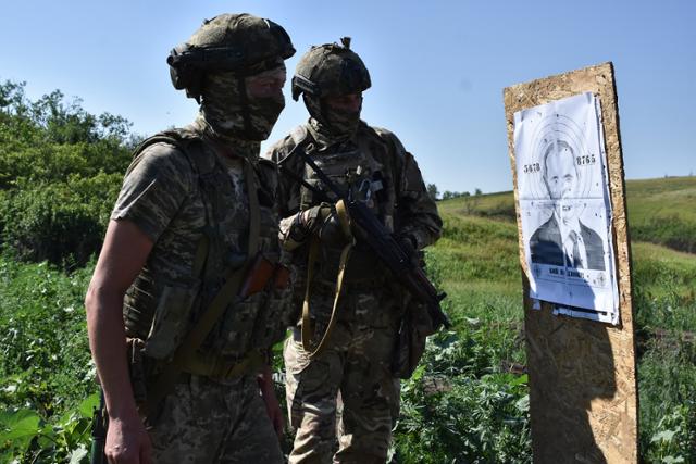 우크라이나 병사들이 지난 18일 우크라이나 자포리자 최전선에서 블라디미르 푸틴 러시아 대통령 얼굴이 그려진 표적지를 두고 사격 훈련을 하고 있다. 자포리자=AP 뉴시스