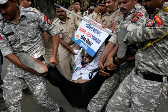 21일 인도 뭄바이에서 의대 입시 부정을 규탄하고 재시험 등을 요구하는 시위를 벌이던 야당 관계자가 경찰에 끌려가고 있다. 뭄바이=AP 연합뉴스