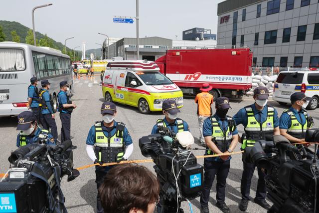 24일 경기 화성시 일차전지(리튬) 제조업체인 아리셀 공장 화재 수습 현장에서 구급차량이 현장을 빠져나오는 가운데, 현장에 배치된 경찰들이 마스크를 쓰고 있다. 뉴스1