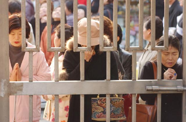 2003학년도 수능 당일, 서울 종로구 경복고에서 학부모들이 손을 모아 기도하고 있다. 조영호 기자