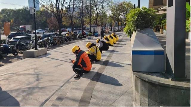 지난달 27일 오전 중국 베이징 차오양구의 한 쇼핑몰 입구 앞. 음식 배달 라이더들이 계단에 앉아 휴대폰을 들여다보고 있다. 중국 대도시 상가 근처에서는 