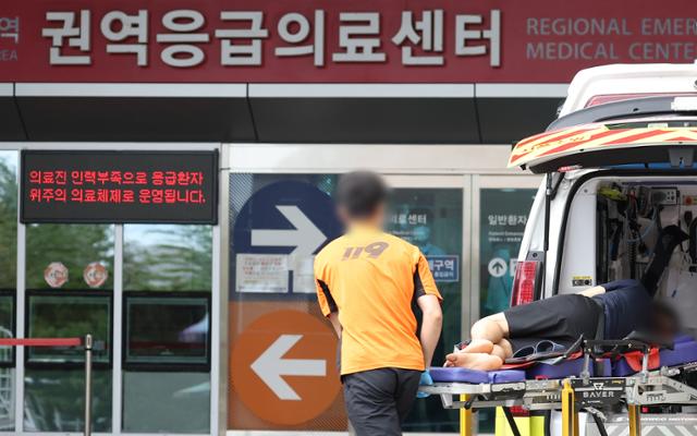 On the morning of the 22nd, a patient is being escorted past a notice stating that the emergency room operates on a system focusing on emergency patients due to a shortage of emergency room personnel at a large hospital emergency medical center in downtown Seoul. Yonhap News