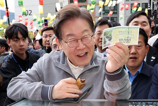 민심을 청취하는 '경청 투어'에 나선 이재명 더불어민주당 대선후보가 3일 강원도 태백시 장성중앙시장에서 잉어빵을 구매하기 위해 태백사랑상품권을 꺼내 보이고 있다. 태백=뉴시스