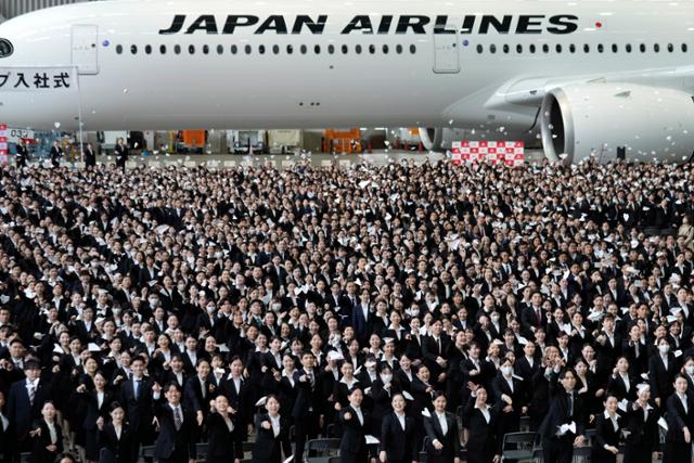 일본항공(JAL) 신입사원들이 지난해 4월 1일 도쿄 하네도공항 비행기 정비 격납고에서 열린 입사식에 참석해 종이비행기를 던지고 있다.도쿄=EPA 연합뉴스