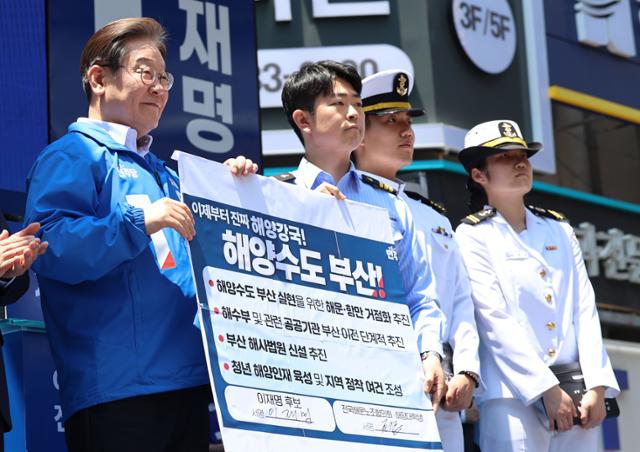 이재명 더불어민주당 대선 후보가 14일 부산 진구 서면 젊음의 거리에서 열린 유세에서 권기흥 에이치라인해운해상직원노조 위원장과 해양수도 부산 협약서에 서명한 후 기념 촬영하고 있다. 연합뉴스